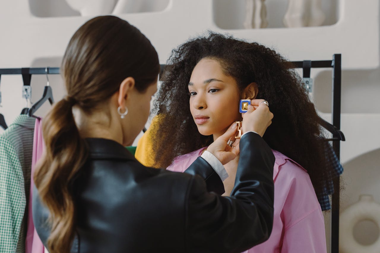 A stylist adjusting a model's earrings in a modern fashion studio setting indoors.